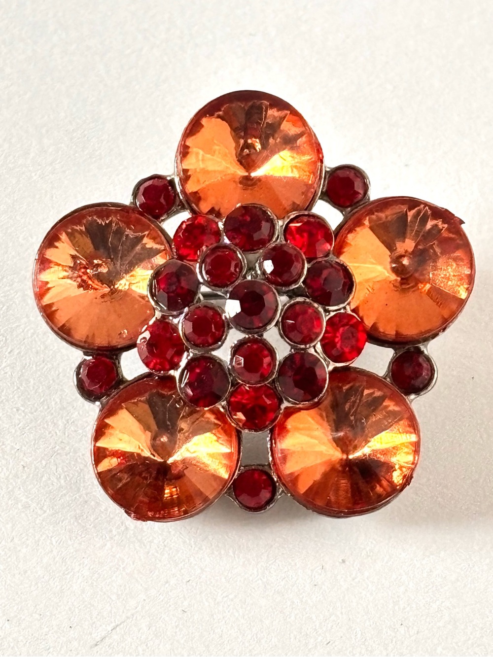 Flower-shaped brooch decorated with large orange rhinestones and small red